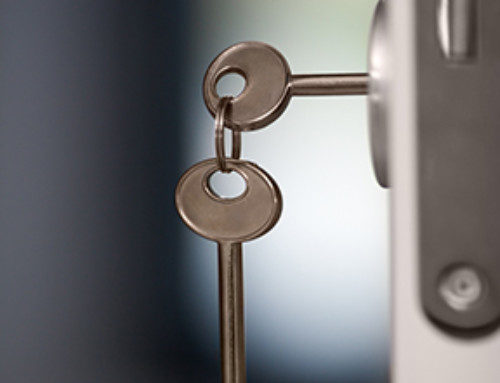 Close-up shot of keys in the lock of open door. One key is in lock another hanging on the ring