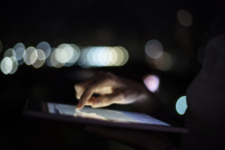 Close up of woman´s hand using digital tablet at night with lights in the background