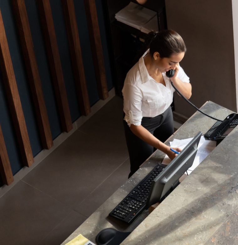 Latin american hotel receptionist taking a phonecall