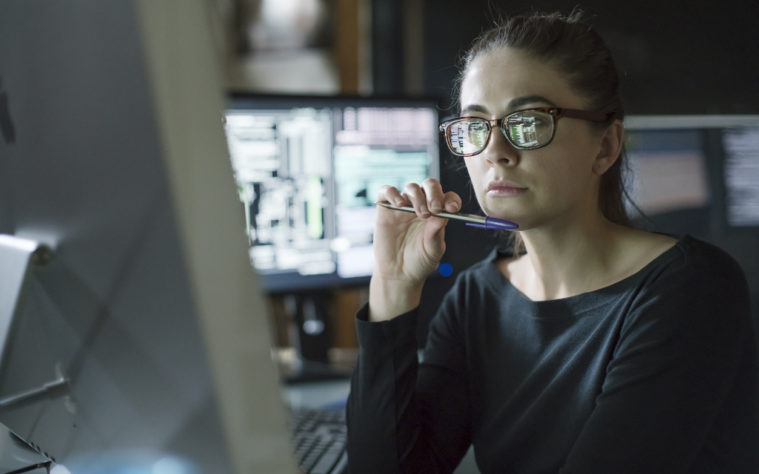 Woman monitors dark office