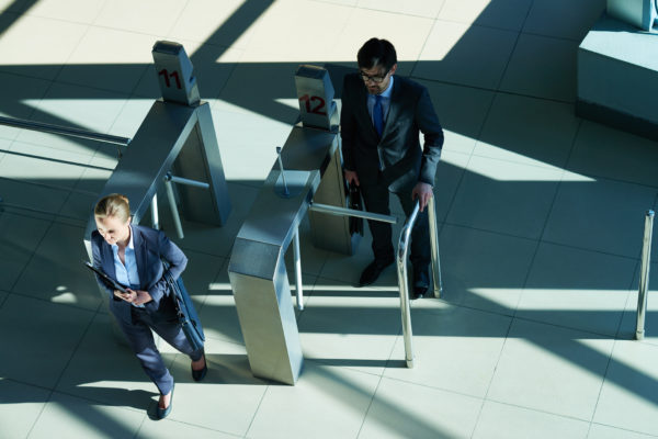High angle view of several business people passing turnstile on the way to work, crossing sunlit business hall